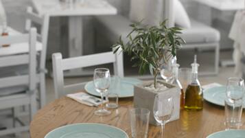 A dining table set with plates, glasses, and a bottle, surrounded by chairs and a potted plant.