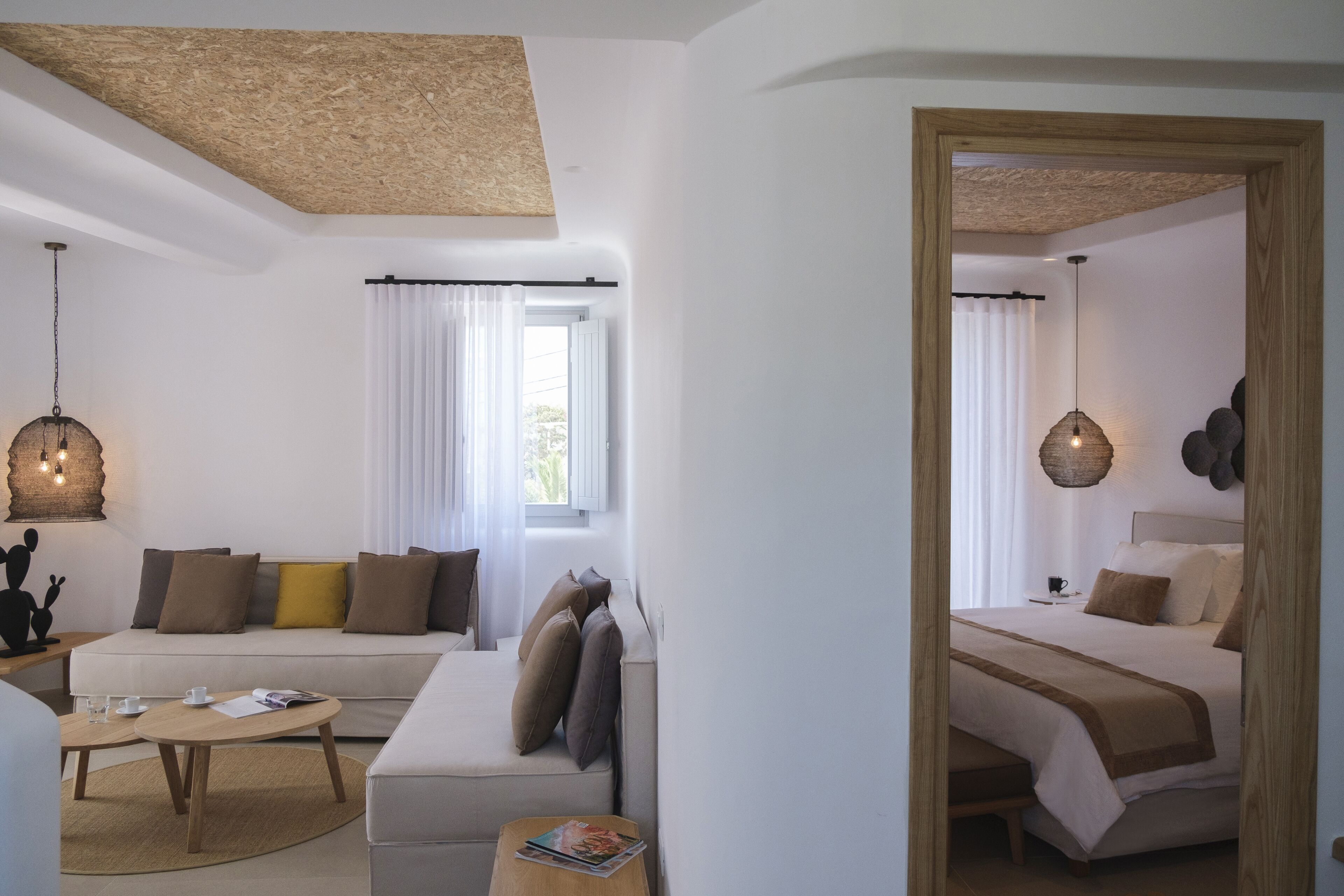 Una habitación de hotel moderna con un sofá, una cama, una mesita de centro y una lámpara colgante.