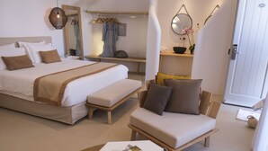A modern bedroom with a large bed, a sofa, a small table, and a mirror. - Argo Hotel (Mykonos)