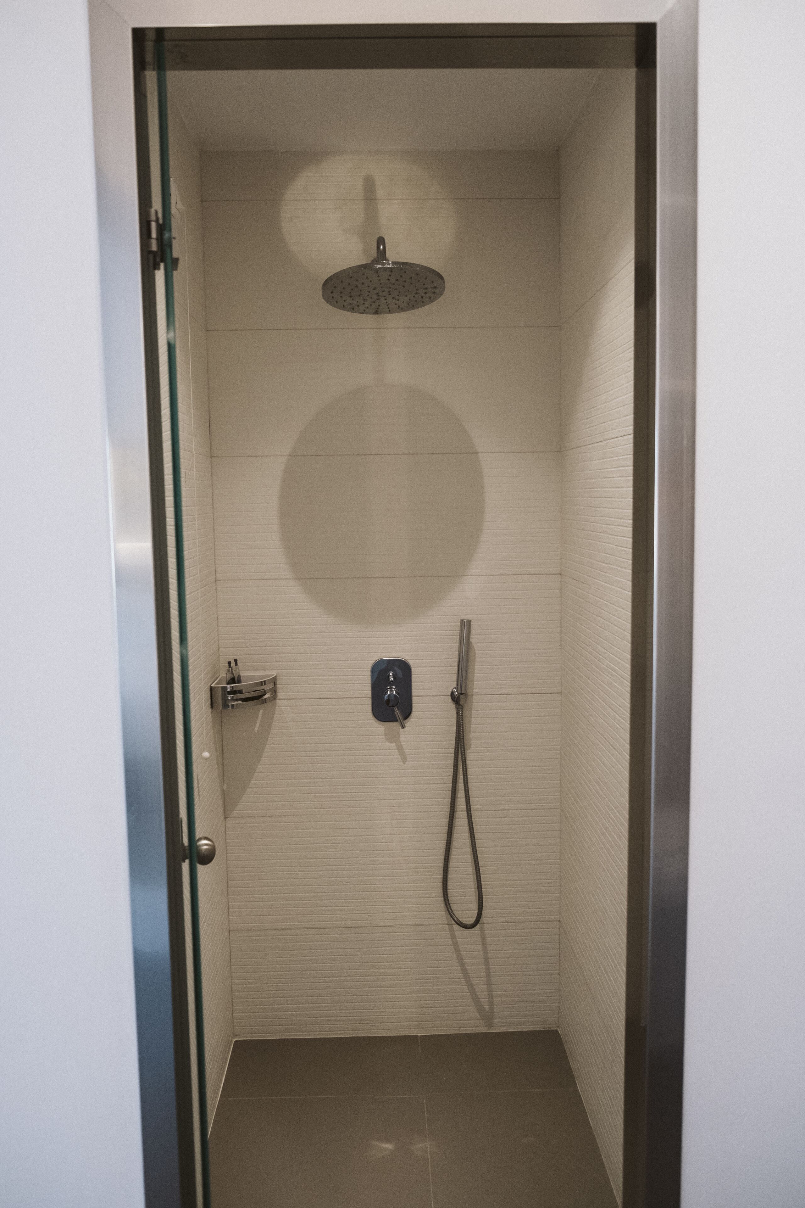 A modern shower with a handheld showerhead and a handheld hose.