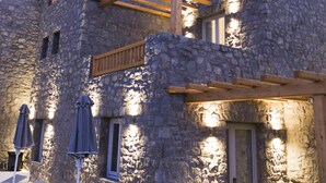 A stone building with a balcony, lounge chairs, and umbrellas. - Argo Hotel (Mykonos)