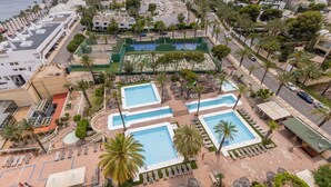 Vista aérea de un resort con múltiples piscinas, palmeras y una zona de playa.
