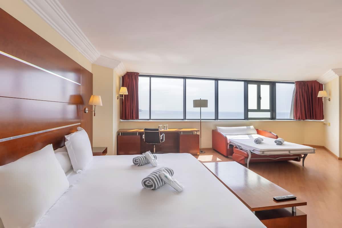 Una habitación de hotel con una cama grande, un escritorio, una silla y una mesita.