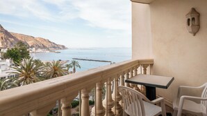 Un balcón con mesa y sillas, con vistas a la costa, montañas y un muelle.