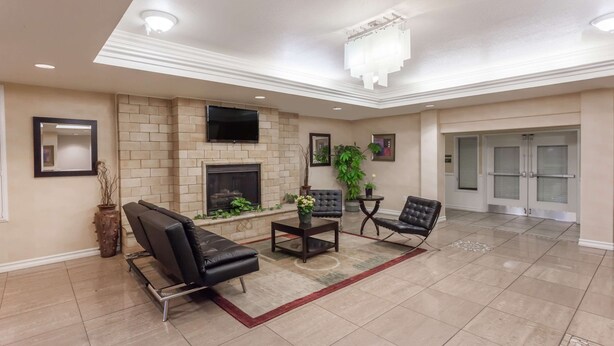 A spacious lobby with a fireplace, leather seating, and a television mounted on the wall. - Hawthorn Suites by Wyndham Victorville (Victorville)