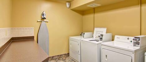 A laundry room with two front-loading washers and dryers, a towel rack, and a countertop.