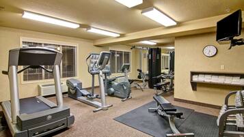Une salle de sport équipée de tapis de course, de vélos elliptiques et de bancs de musculation.