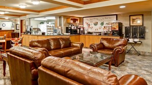 A lobby with leather sofas, a coffee bar, and a large mirror. - Ramada by Wyndham Ponoka (Ponoka)