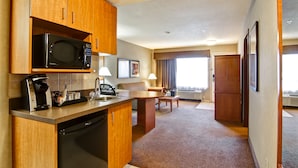 A compact hotel room with a kitchenette, a dining area, and a large window. - Ramada by Wyndham Ponoka (Ponoka)