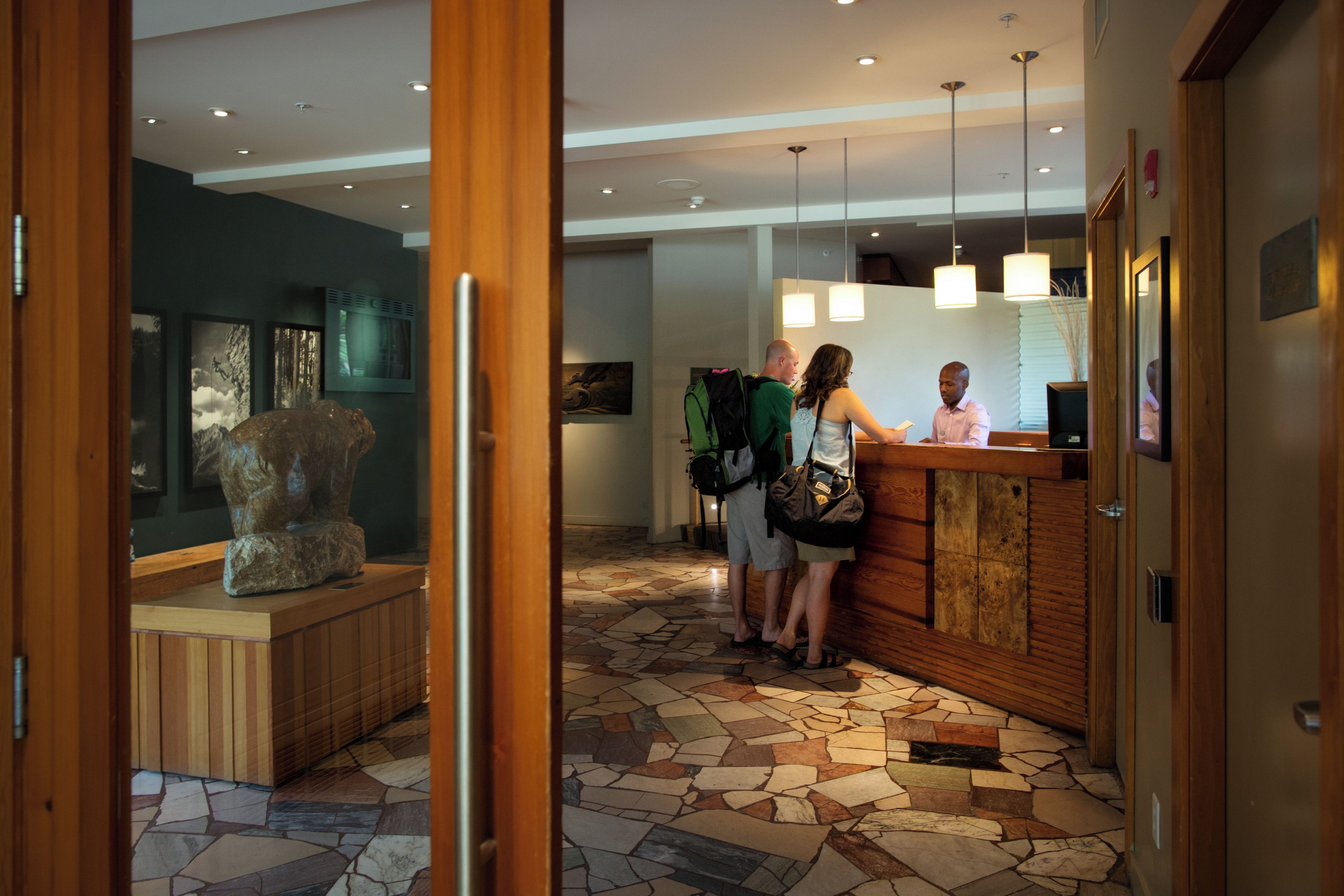 A reception area with a reception desk, a stone-tiled floor, and a sculpture on display.