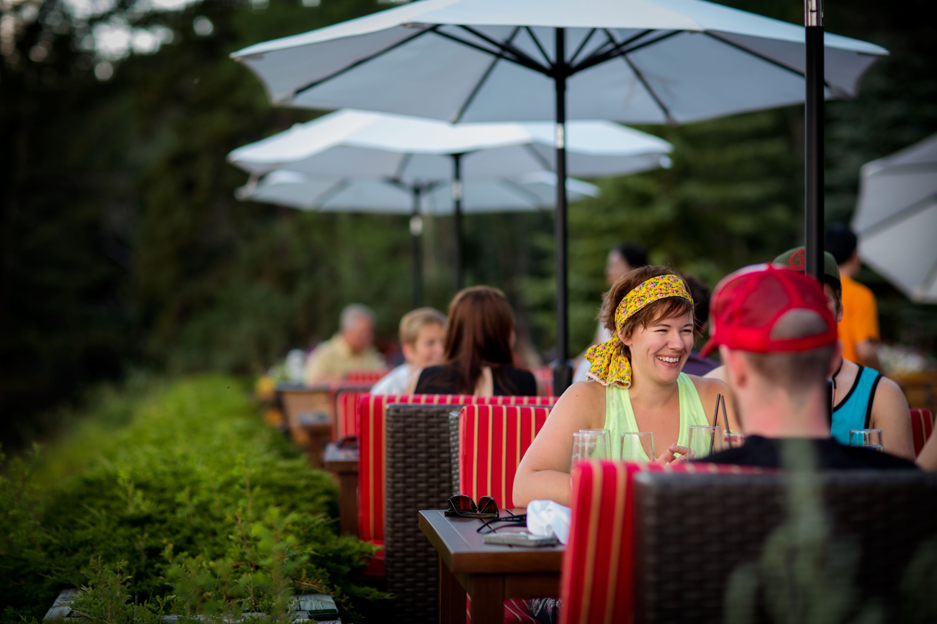 A restaurant with outdoor seating, red and white striped chairs, and white umbrellas.