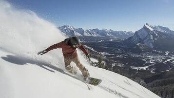 Een snowboarder op een besneeuwde helling, met een bergachtige achtergrond.