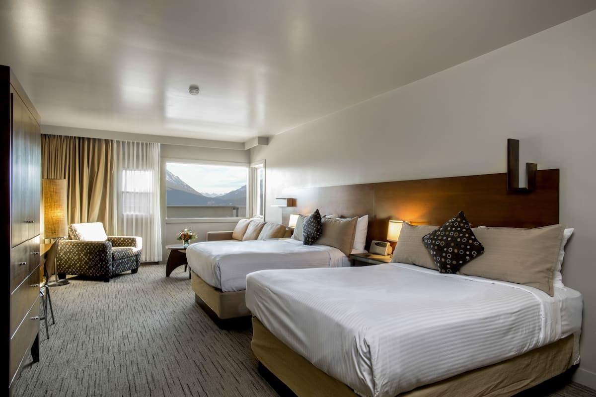 Une chambre d’hôtel avec deux lits, une chaise, un bureau et une vue sur les montagnes.