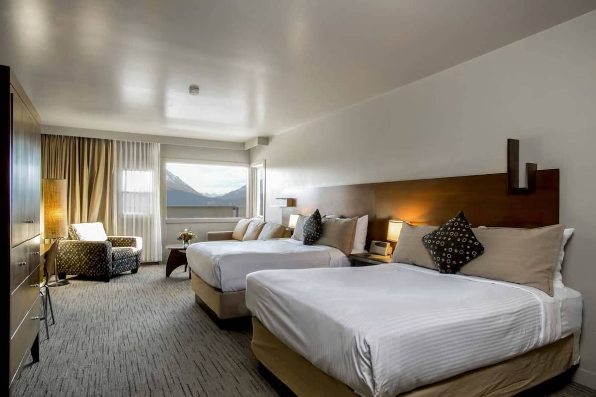 Une chambre d’hôtel avec deux lits, un canapé, un bureau et une vue sur les montagnes.
