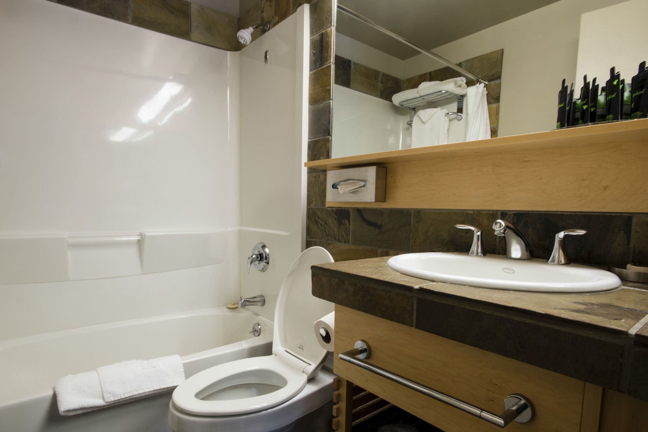 A modern bathroom with a white toilet, a bathtub, a sink, and a mirror above the sink.