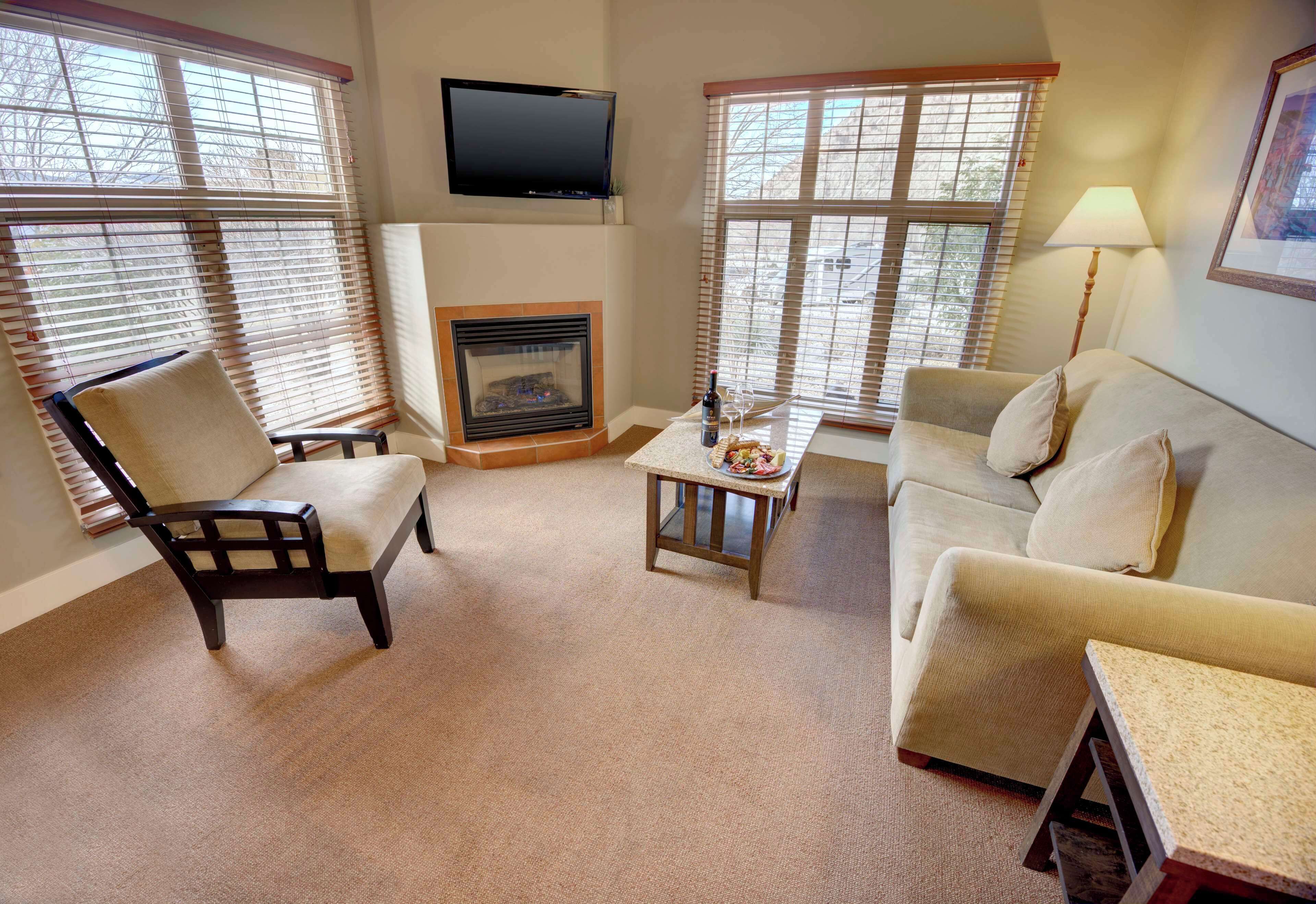 A living room with a fireplace, a television mounted above it, and a sofa.