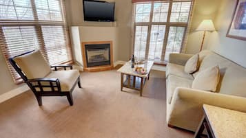A living room with a fireplace, a television mounted above it, and a sofa.