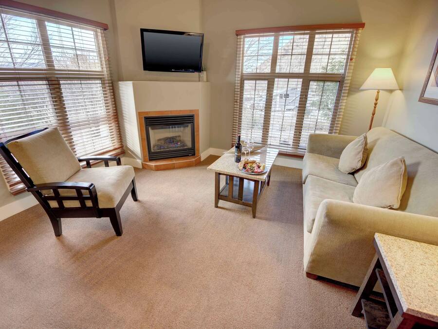 A living room with a fireplace, a television mounted above it, and a sofa.