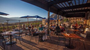An outdoor dining area with tables and chairs, umbrellas, and a view of the landscape. - Spirit Ridge, in The Unbound Collection by Hyatt (Osoyoos)