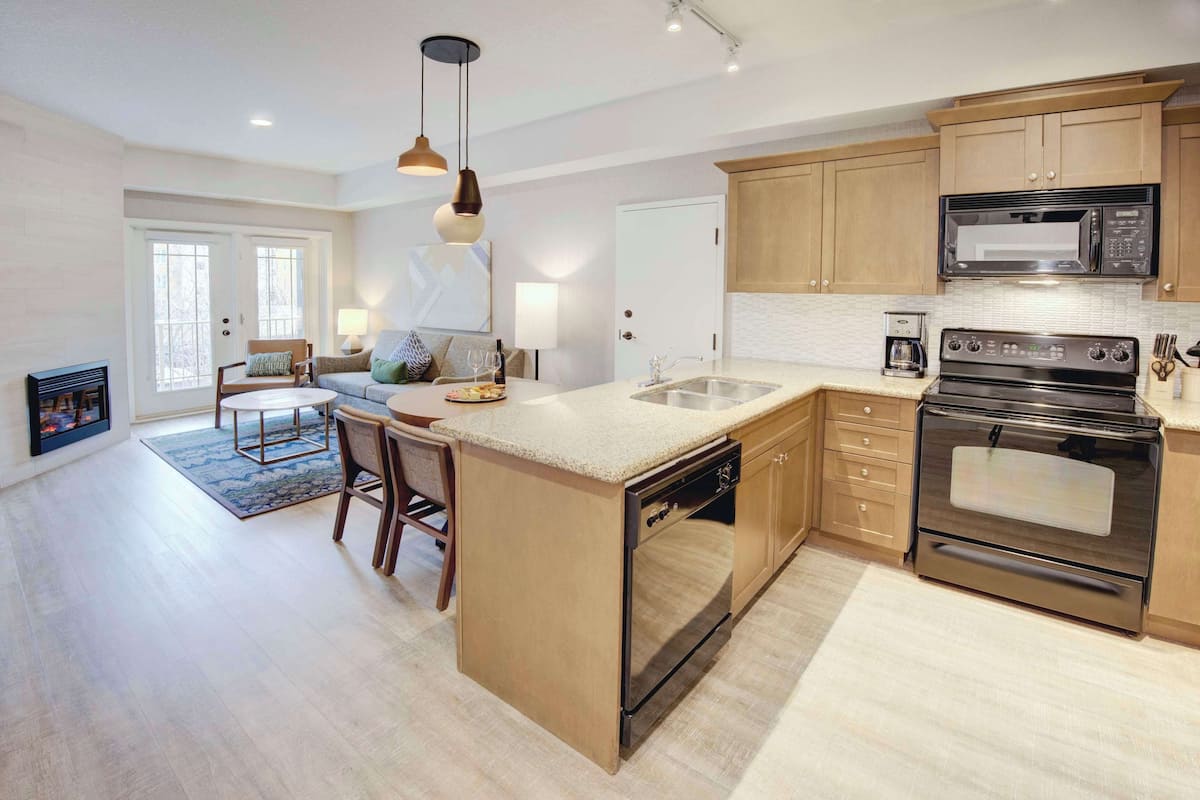 A modern kitchen with wooden cabinets, a built-in oven, and a large island with a sink.