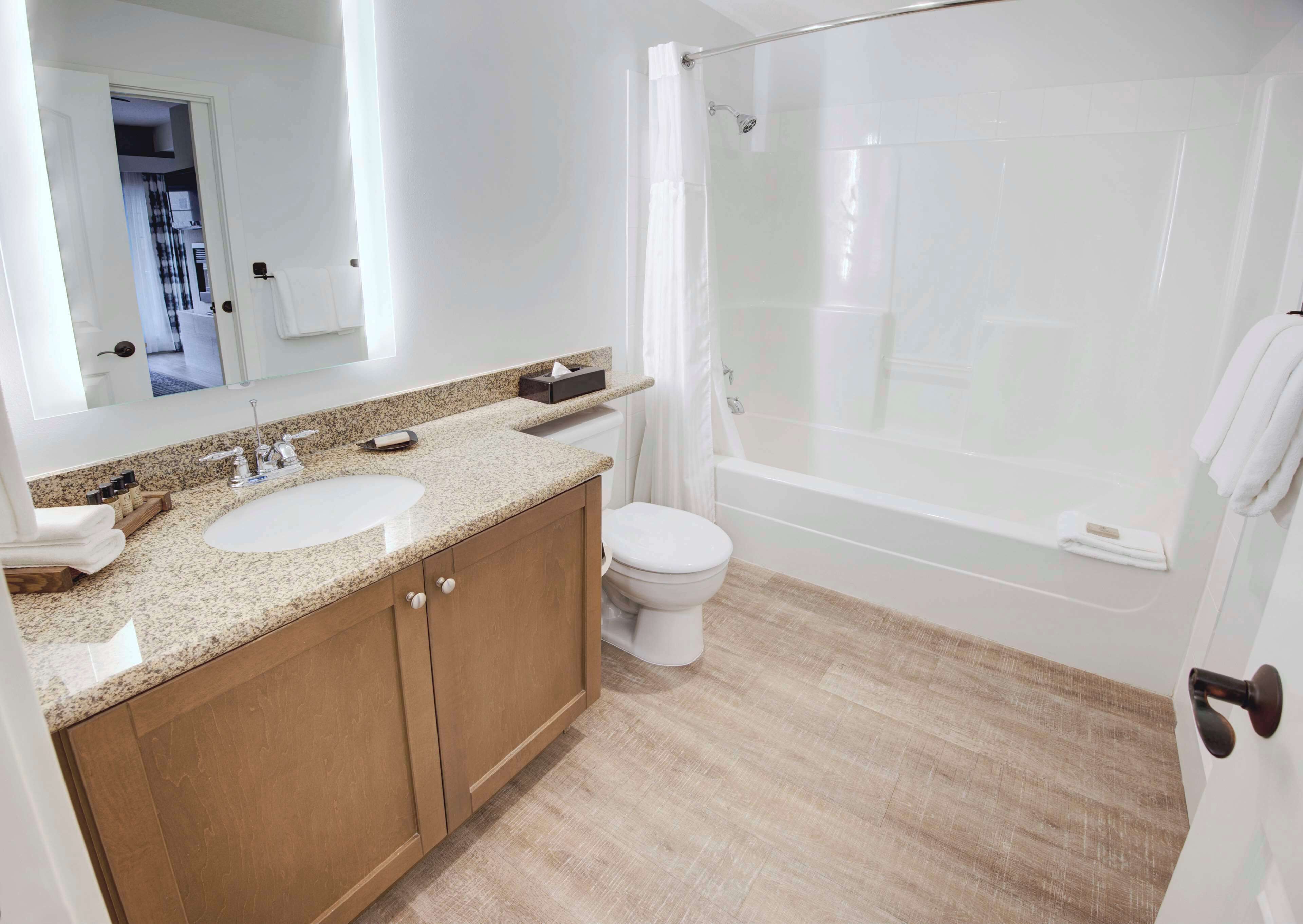 A modern bathroom with a double sink, a toilet, a shower, and a large mirror.