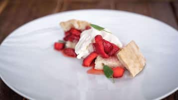 A dessert on a white plate with strawberries and whipped cream.