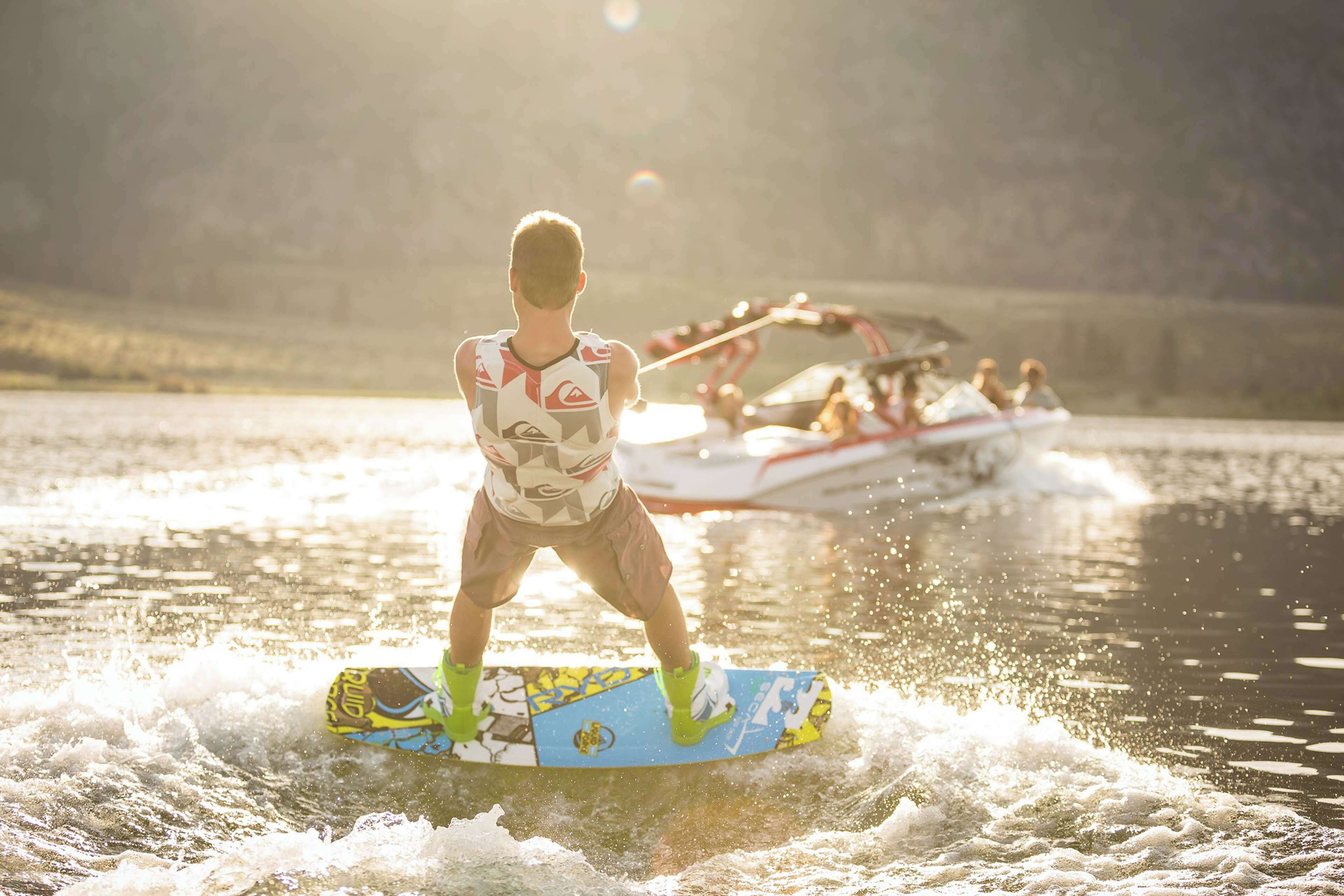 A person wakeboarding on a body of water with a boat in the background.