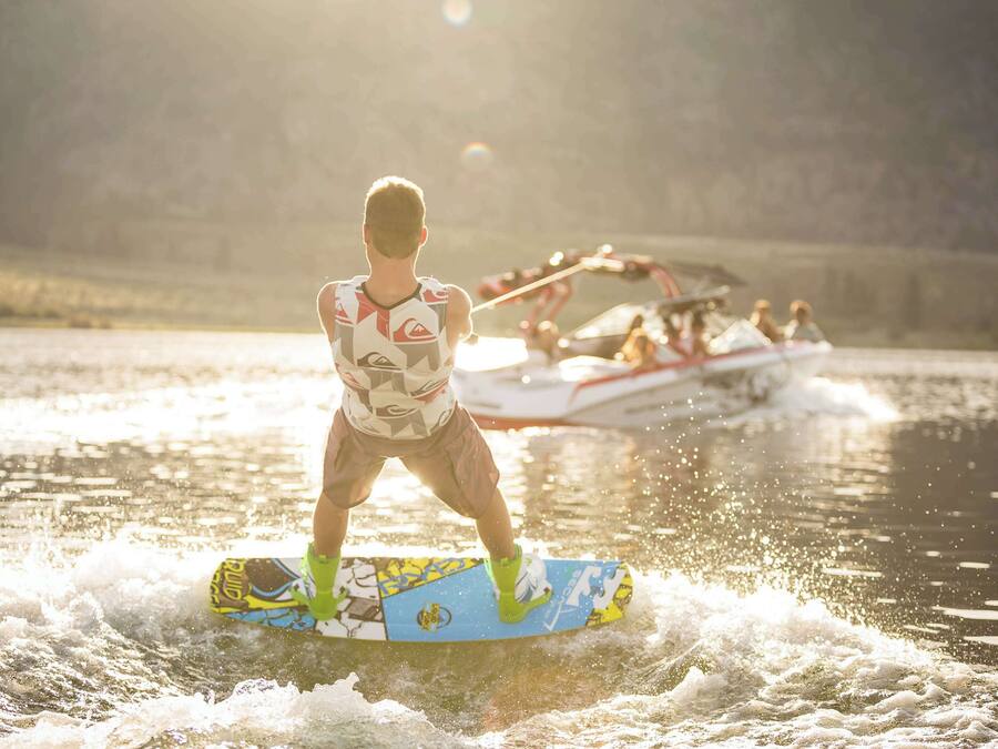 A person wakeboarding on a body of water with a boat in the background.