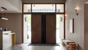 A modern interior with a central door, a reception desk, a bench, and a wall-mounted light fixture. - Spirit Ridge, in The Unbound Collection by Hyatt (Osoyoos)