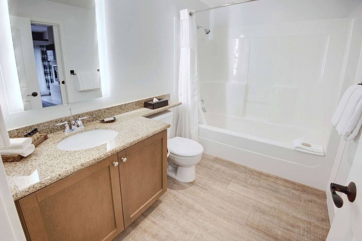 A bathroom with a double sink, toilet, and a walk-in shower.