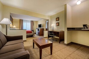 A hotel room with a bed, a desk, a chair, a coffee maker, and a TV.