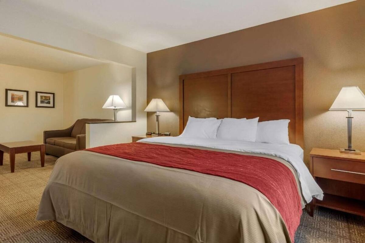 A hotel room with a large bed, two bedside tables, a chair, and a desk.