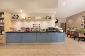 A modern kitchen with a blue island, white tiled backsplash, and a dining area with a green booth.