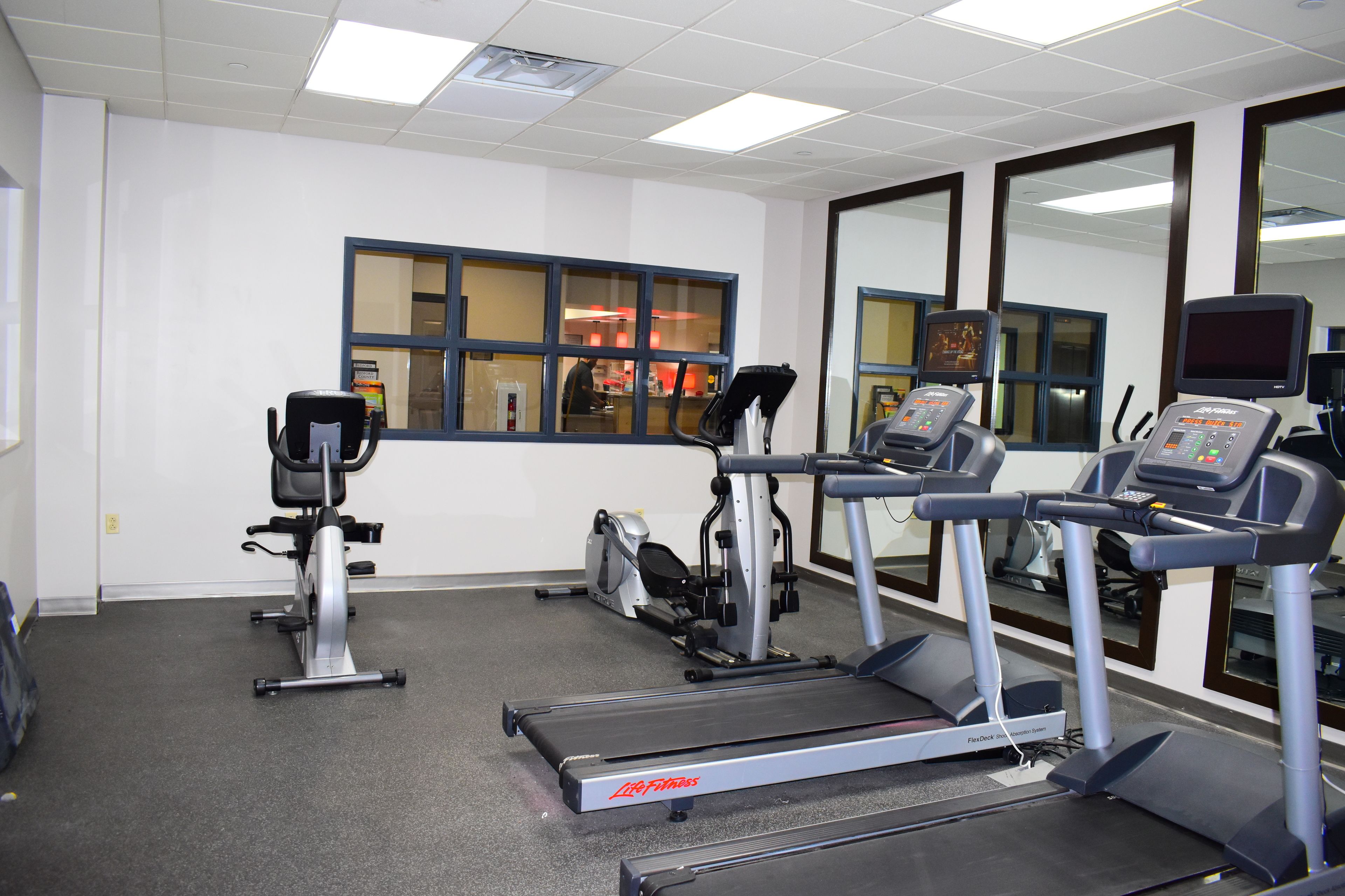 A fitness room with treadmills, stationary bikes, and a rowing machine.