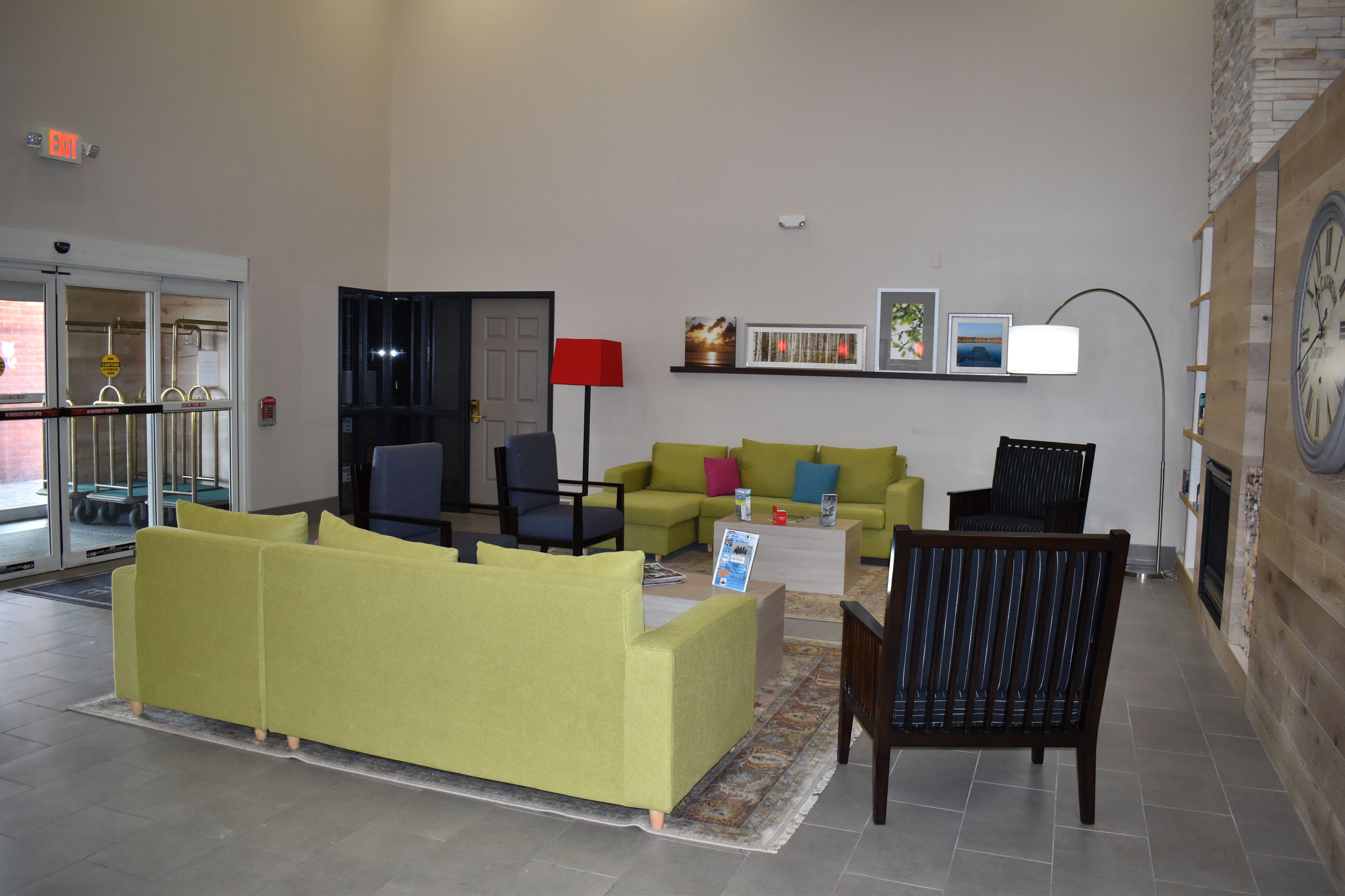 A modern living room with a green sofa, a black chair, and a red floor lamp.