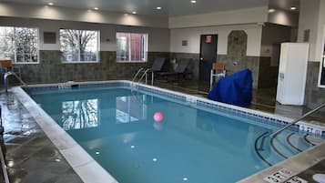 An indoor swimming pool with clear water, marked depth lines, and a pink ball.