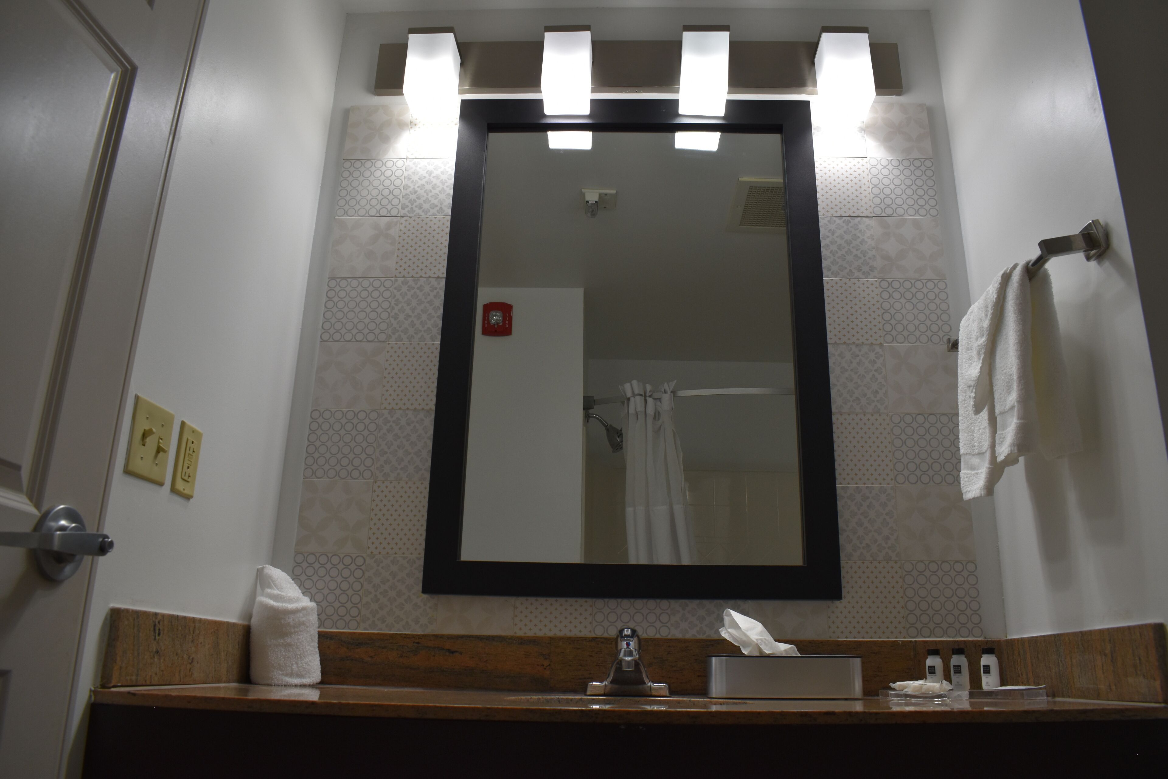 A bathroom with a mirror, towel, sink, and a hand dryer.