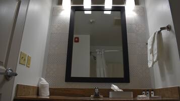 A bathroom with a mirror, towel, sink, and a hand dryer.