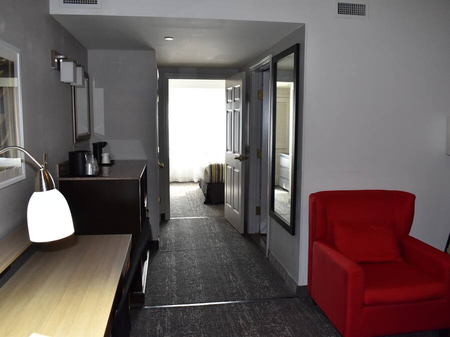 A hotel corridor with a desk, chair, and a red armchair.