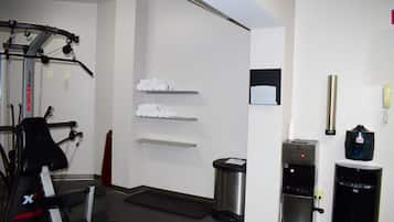 A gym with exercise equipment, a water dispenser, and a trash bin.