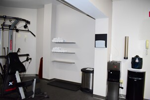 A gym with exercise equipment, a water dispenser, and a trash bin.
