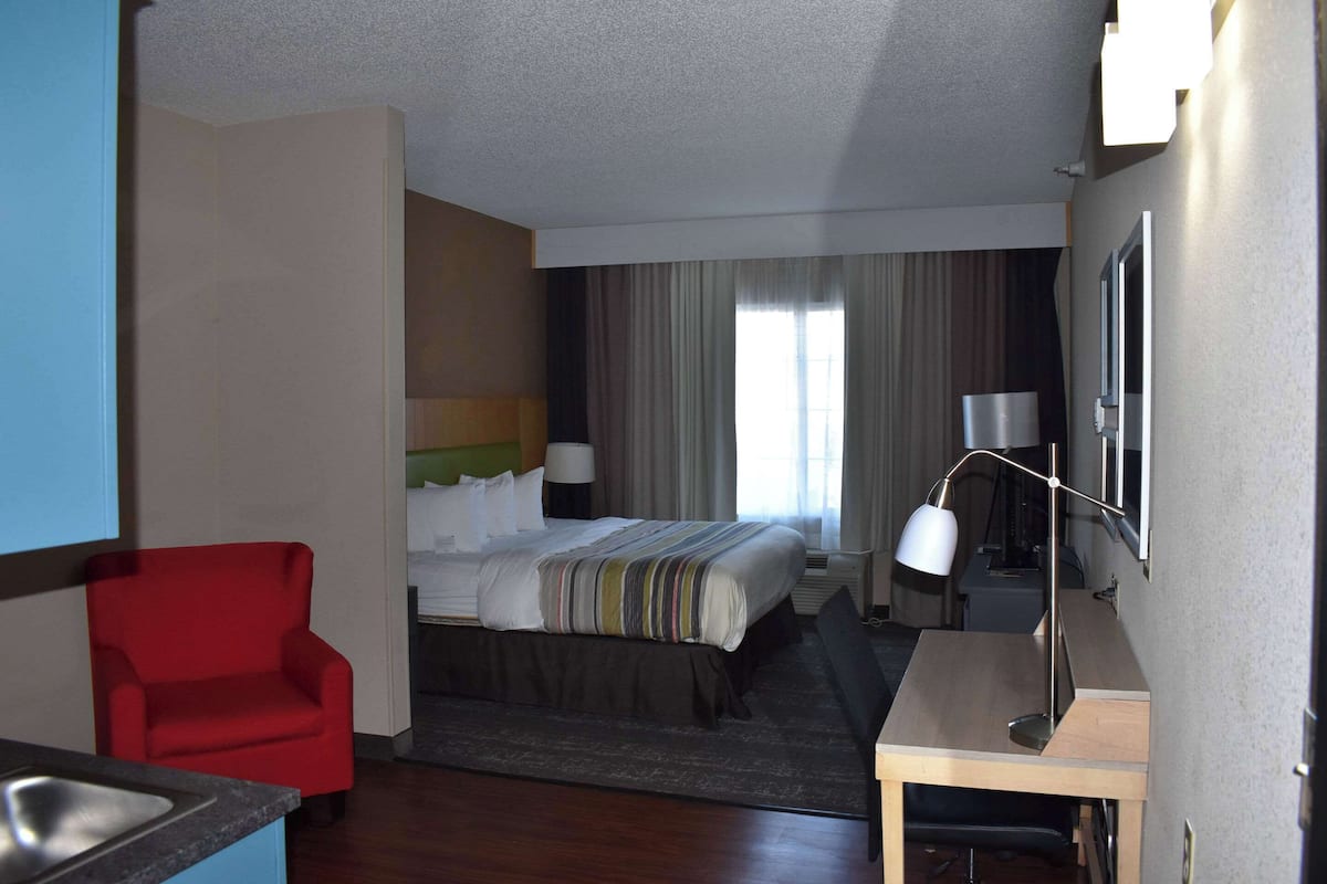 A hotel room with a bed, a desk, a chair, and a sink.
