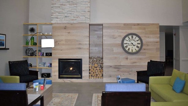 A modern living room with a fireplace, wooden wall paneling, and a large clock.