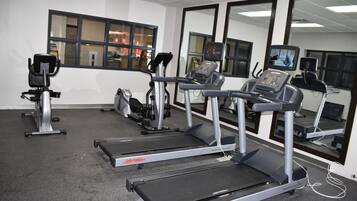 Un gimnasio con cintas de correr, bicicletas estáticas y equipo de ejercicio.