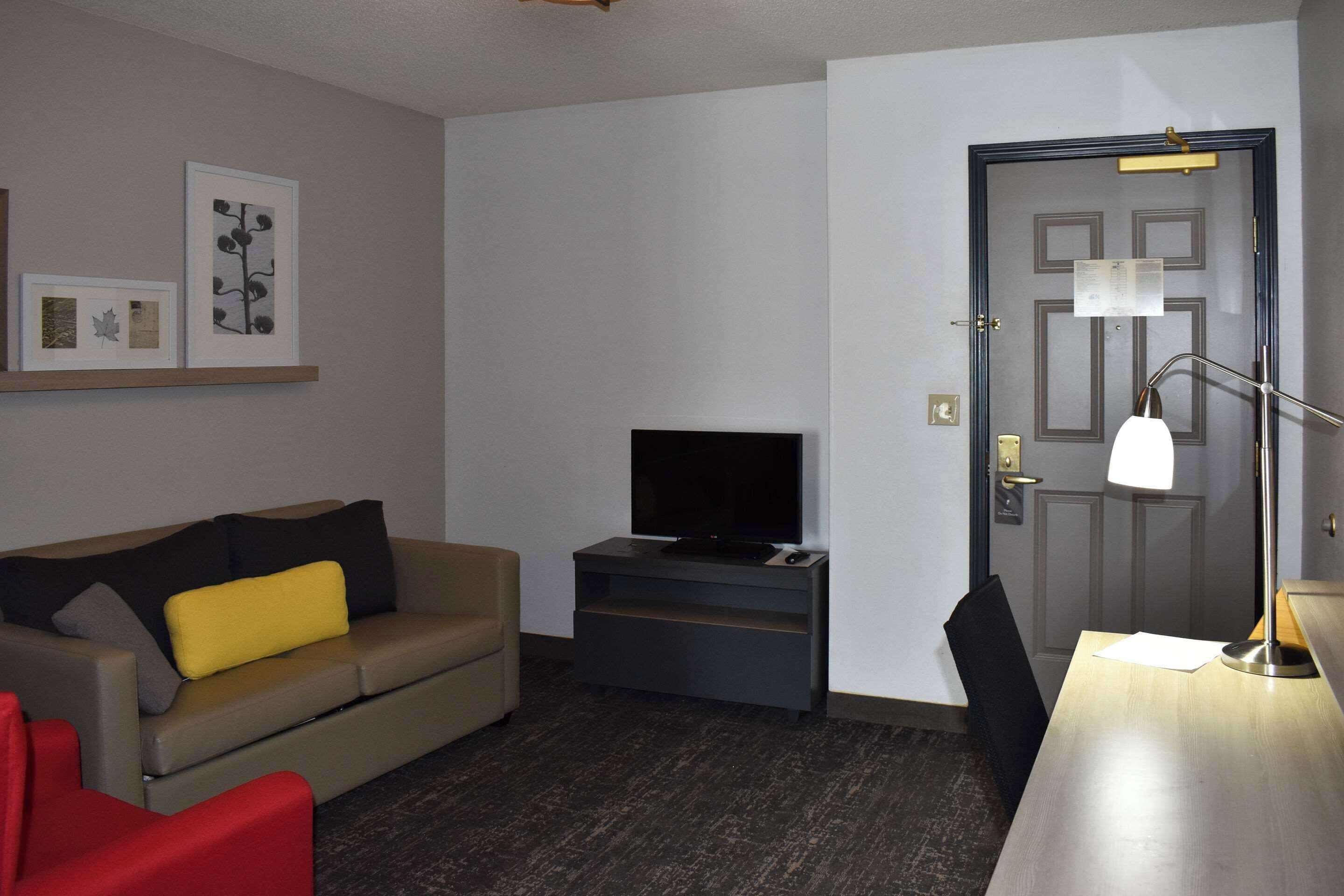 Una sala moderna con un sofá, televisor, escritorio y una puerta.