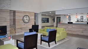 A modern lobby with a wooden wall, a clock, a reception desk, and seating areas.