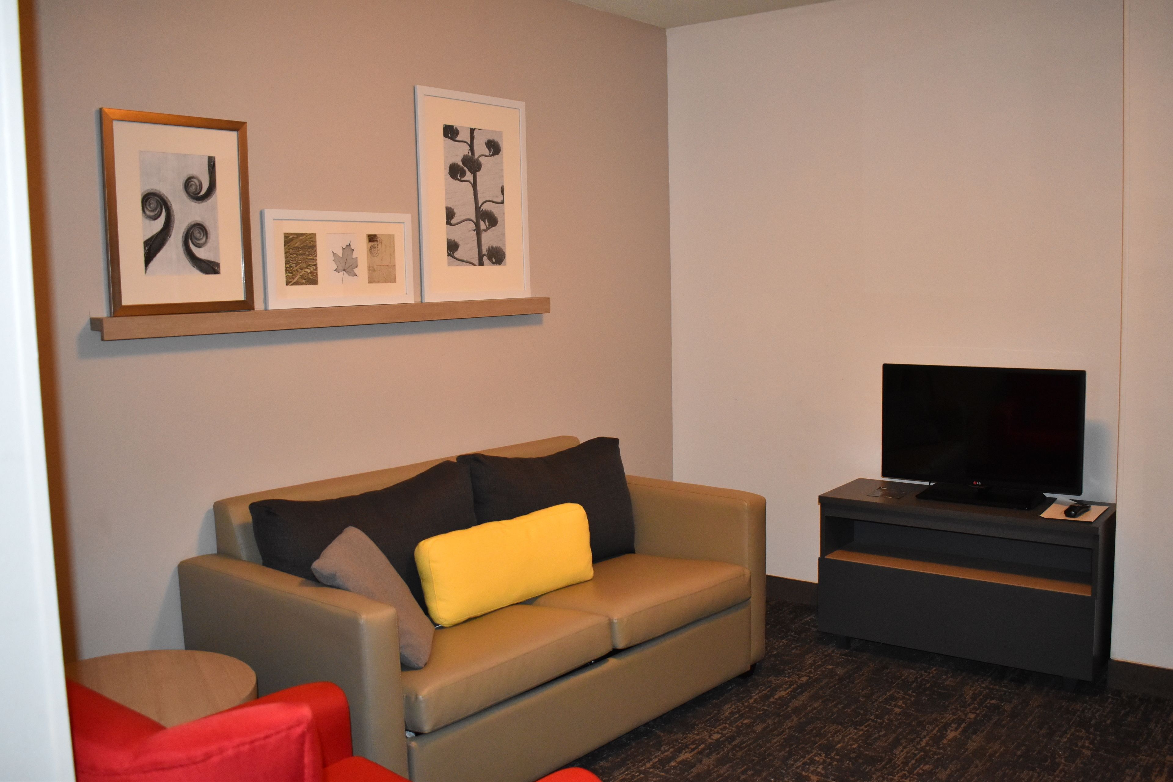 A modern living room with a beige sofa, red armchair, and a flat-screen TV on a black stand.