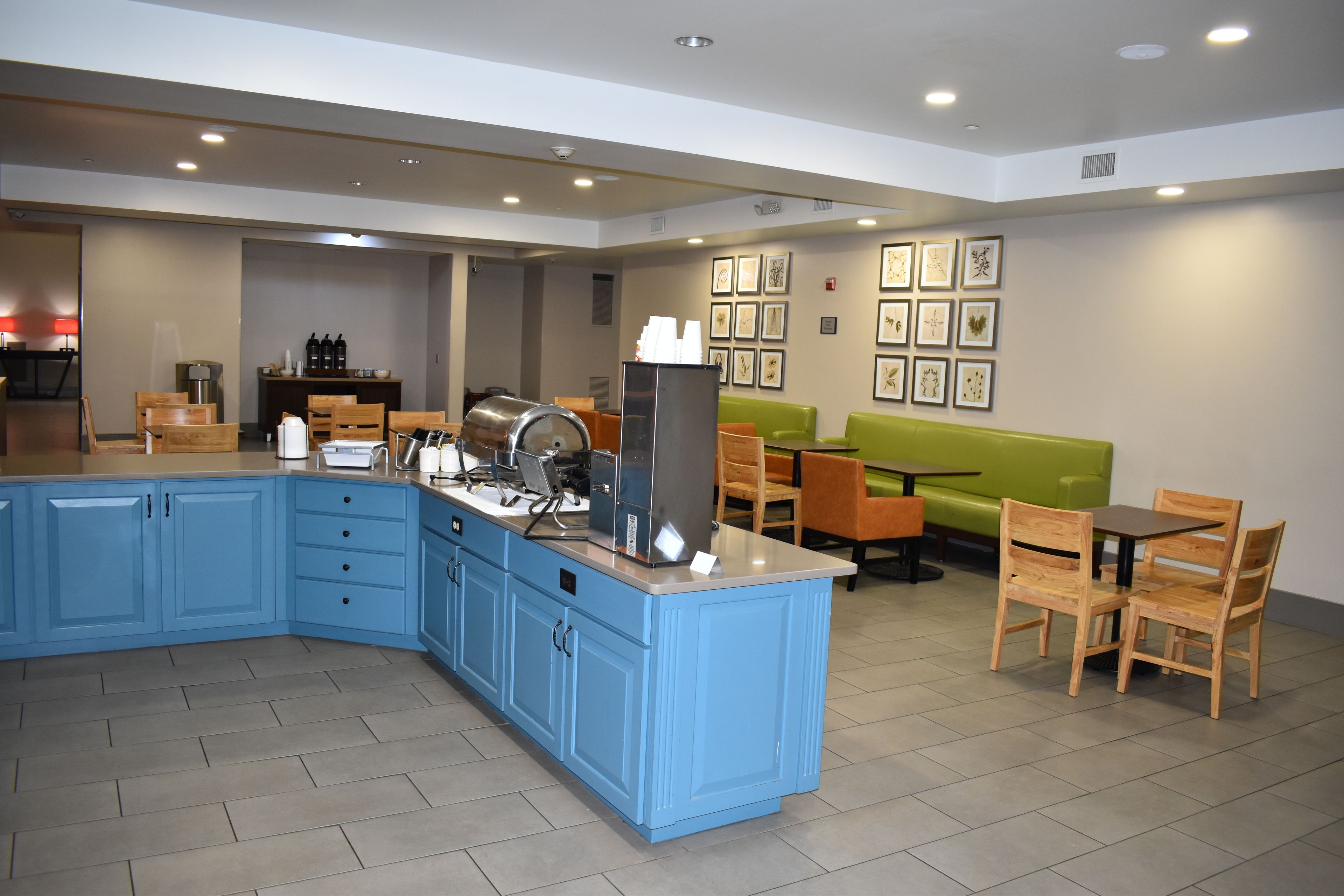 A modern dining area with blue cabinets, a coffee machine, and a green sofa.