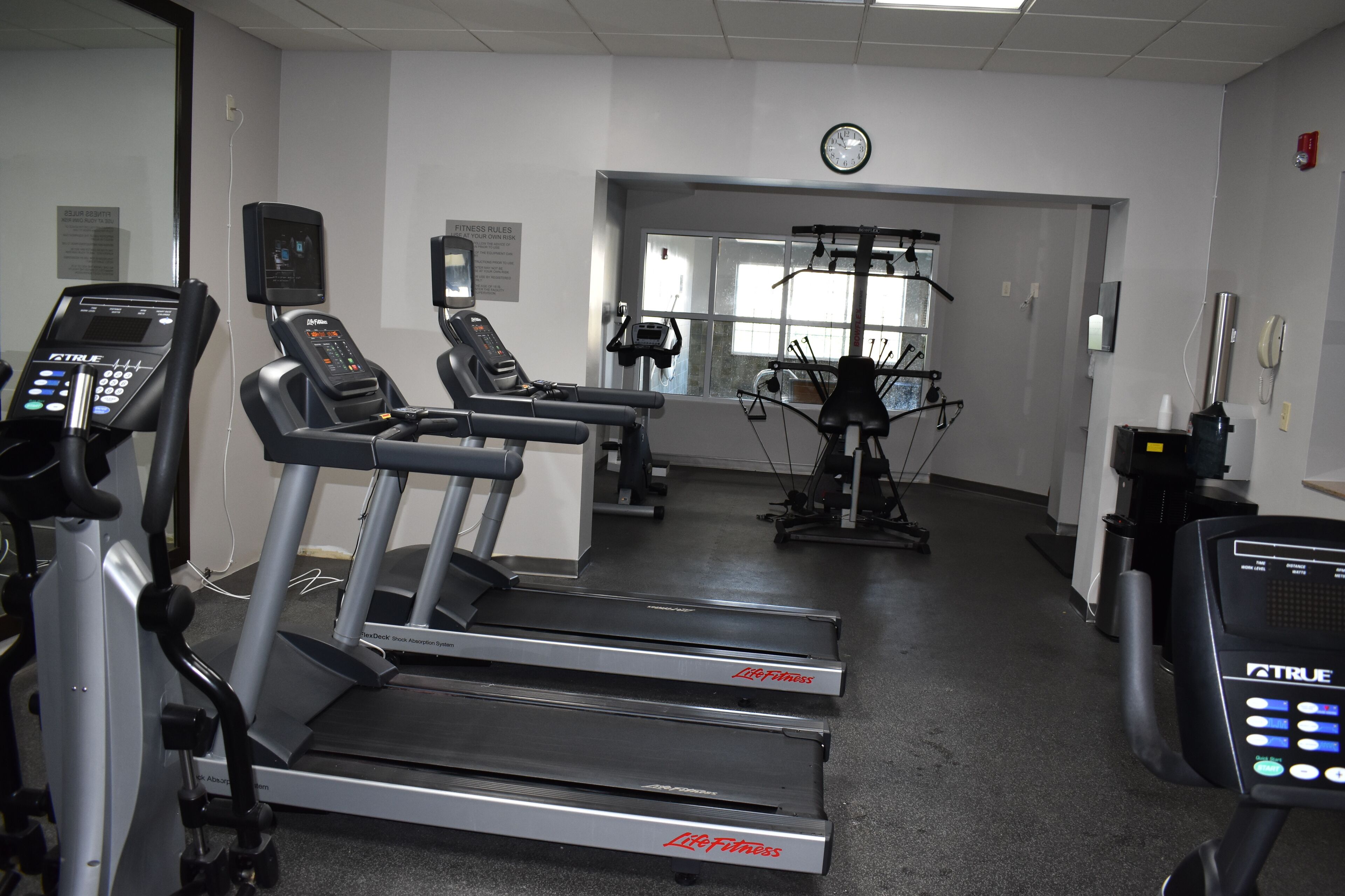 Ein Fitnessstudio mit Laufbändern, Kraftgeräten und einem Spiegel.