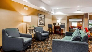 Um saguão de hotel com assentos, uma mesa de atendimento e uma sala de conferências.